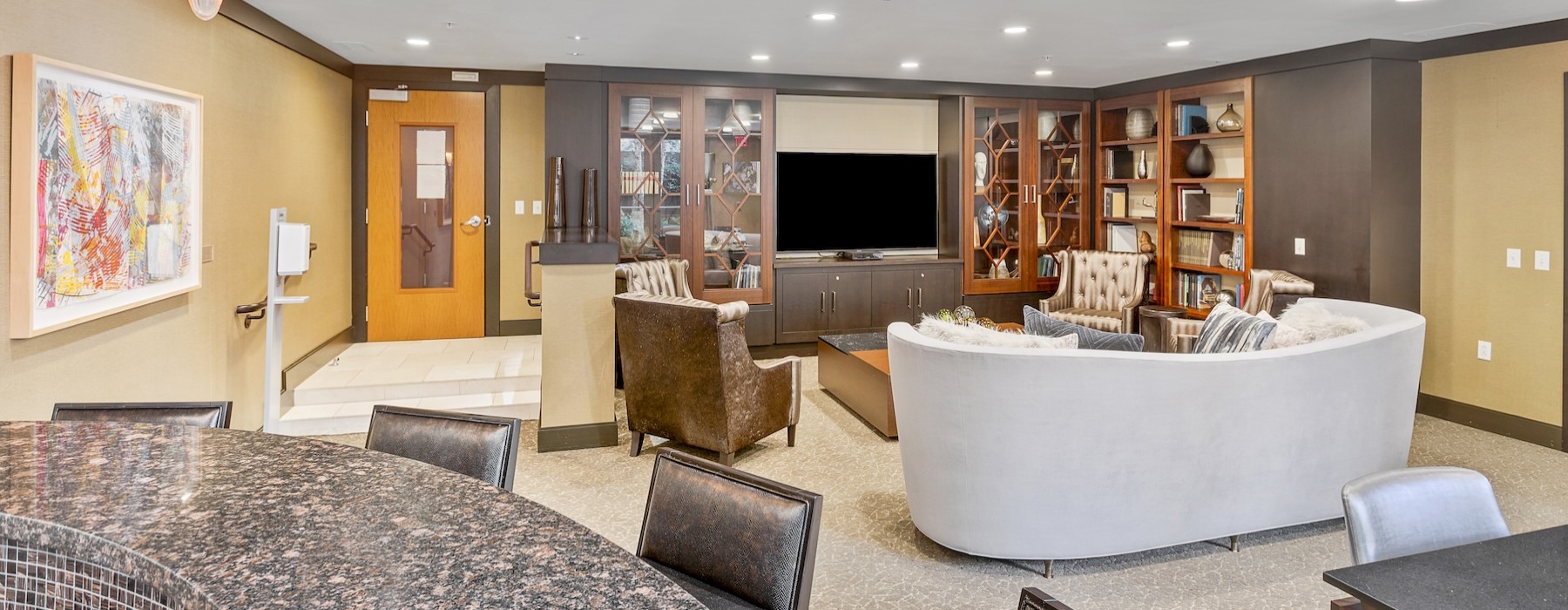 a lounge with a tv, couch, tables and chairs